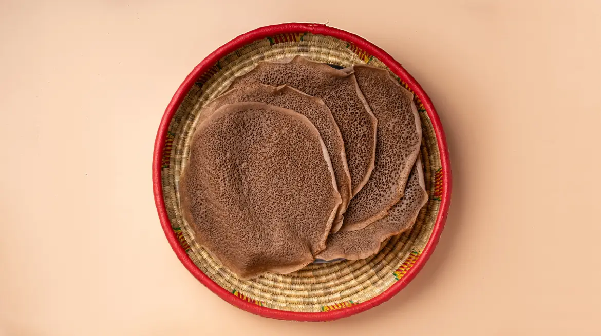 Frische Injera-Fladen aus Teff in einem rot umrandeten geflochtenen Korb